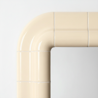 Close-up of the rounded corner of a Soft Butter ceramic-look mirror, showing the glossy surface and visible joint detail.