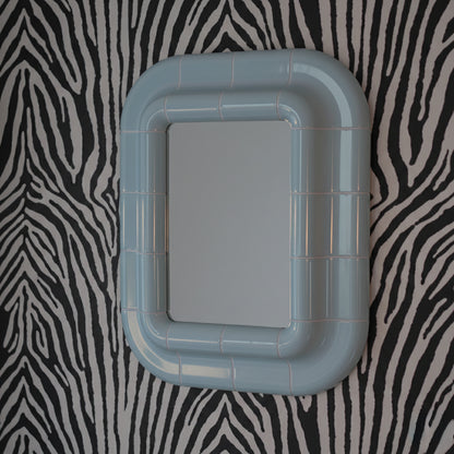 Ice Blue ceramic-look mirror shown in angled perspective, highlighting rounded edges and glossy finish.