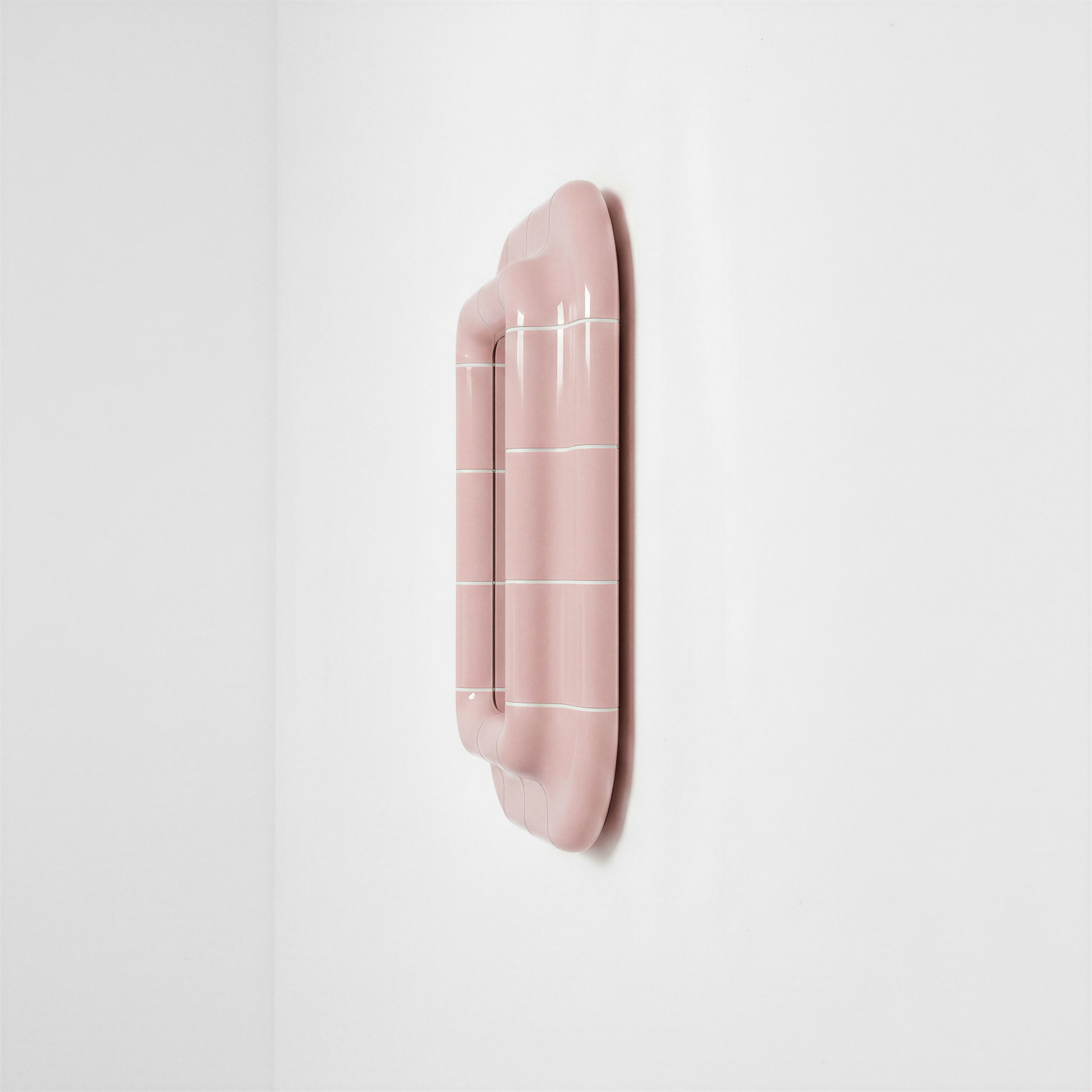 Side view of the blush pink ceramic-look mirror showing its depth and curved frame.