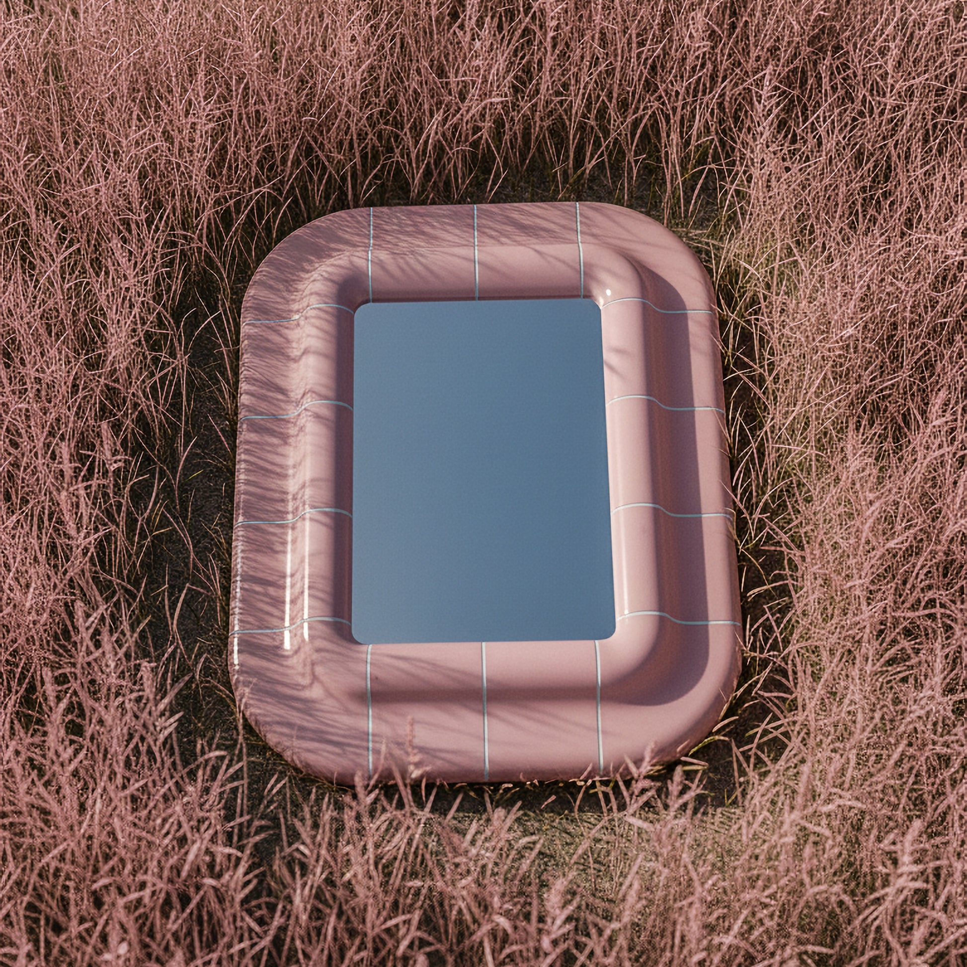 Top view of a pink sculptural mirror with soft curves and glossy finish, surrounded by pink grass, highlighting its shape and reflective glass.