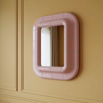 Lolita  rounded mirror in Blush Pink high-gloss lacquer seen from an angle, reflecting a white curtain on an ochre wall
