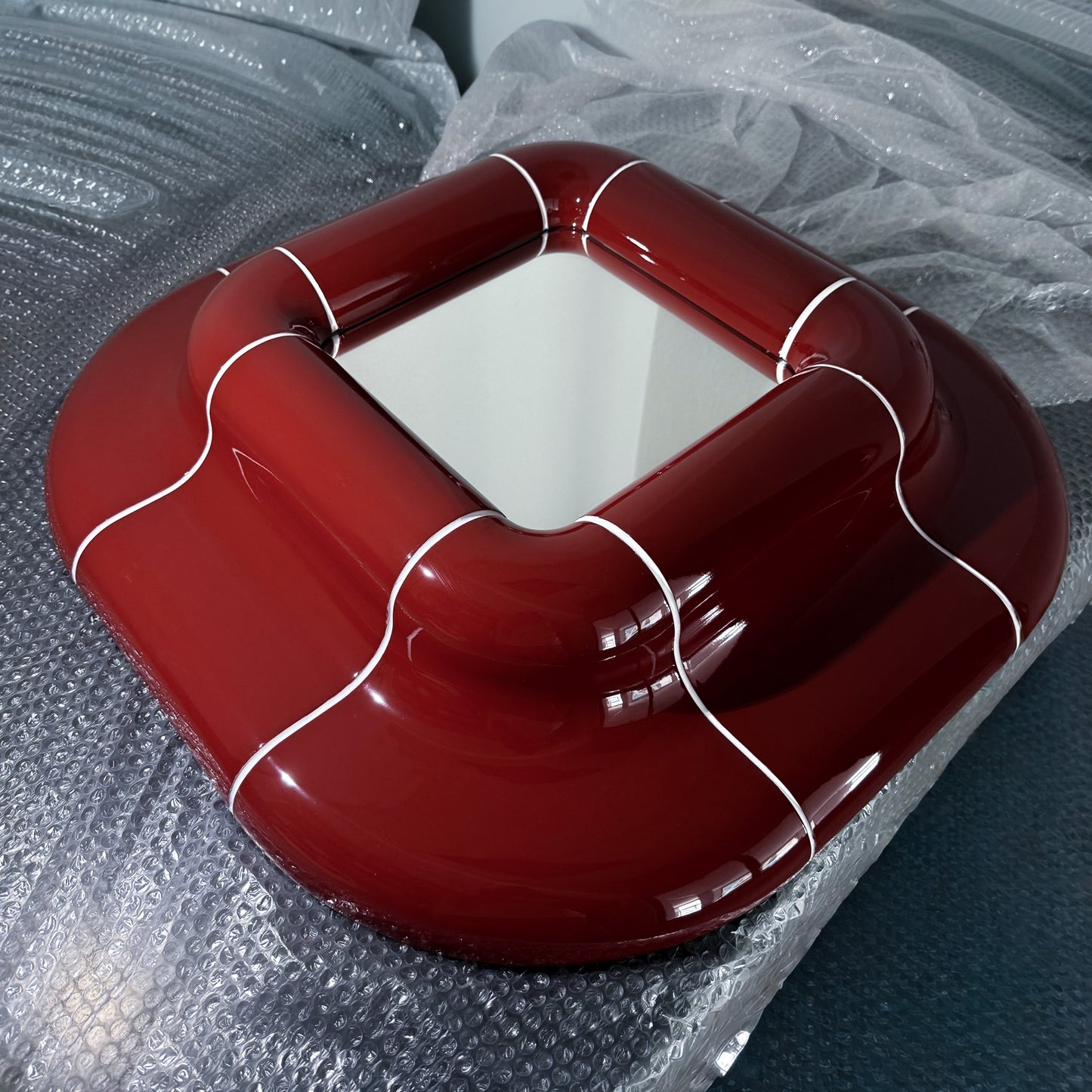 Front view of the Lolo Mirror in Deep Burgundy, a handcrafted glossy modular mirror with rounded geometric design.