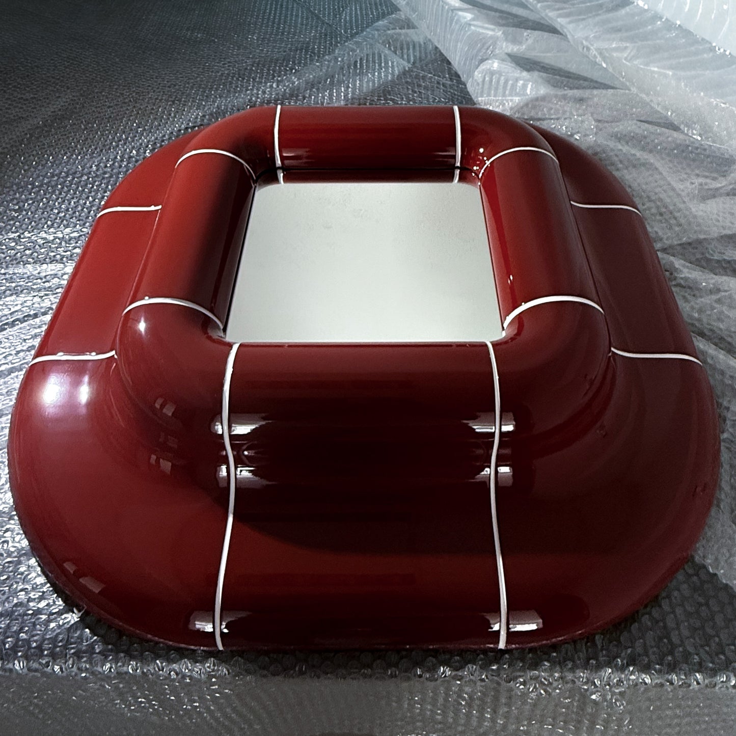 Lolo Mirror in Deep Burgundy photographed from above, showcasing its glossy handcrafted finish and sculptural modular frame.