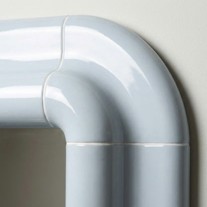 Detail of Lolo ceramic mirror in Ice Blue by Tilecito, rounded glazed tile corner with visible grout lines and glossy finish