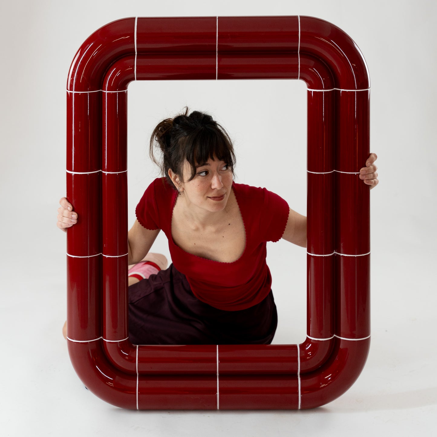 Portalito mirror with model interaction, Deep Burgundy frame emphasizing scale and lightness