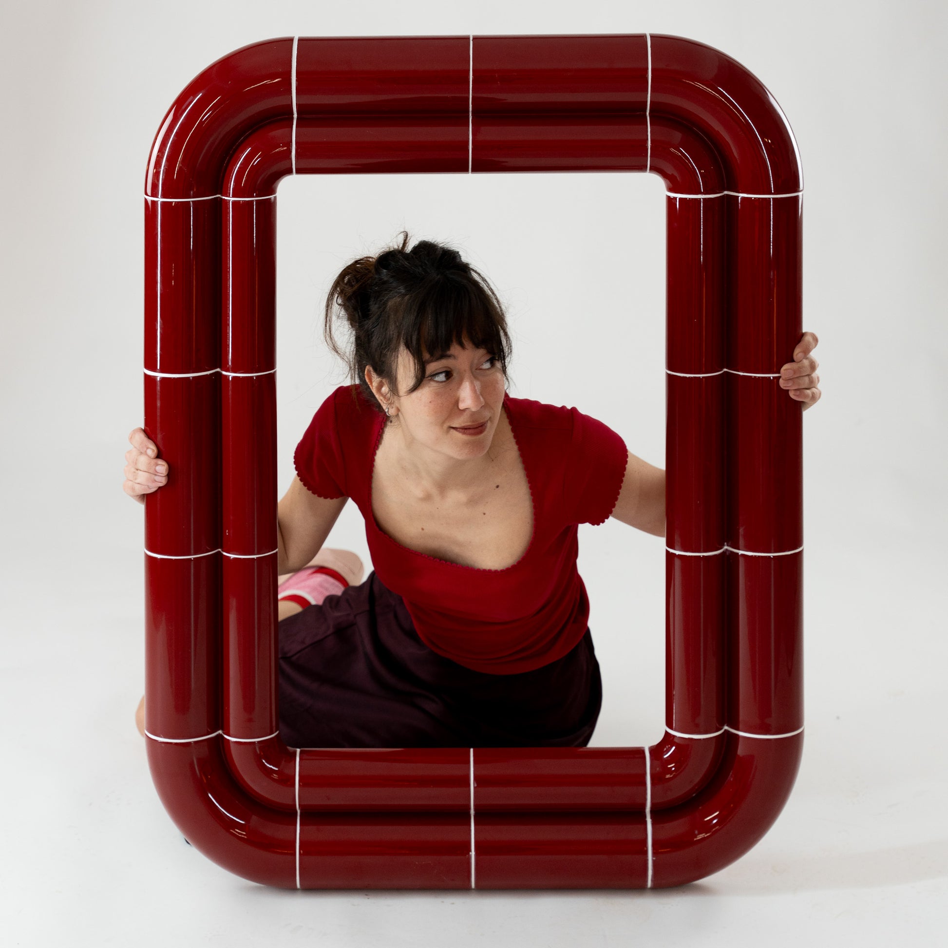 Portalito mirror with model interaction, Deep Burgundy frame emphasizing scale and lightness