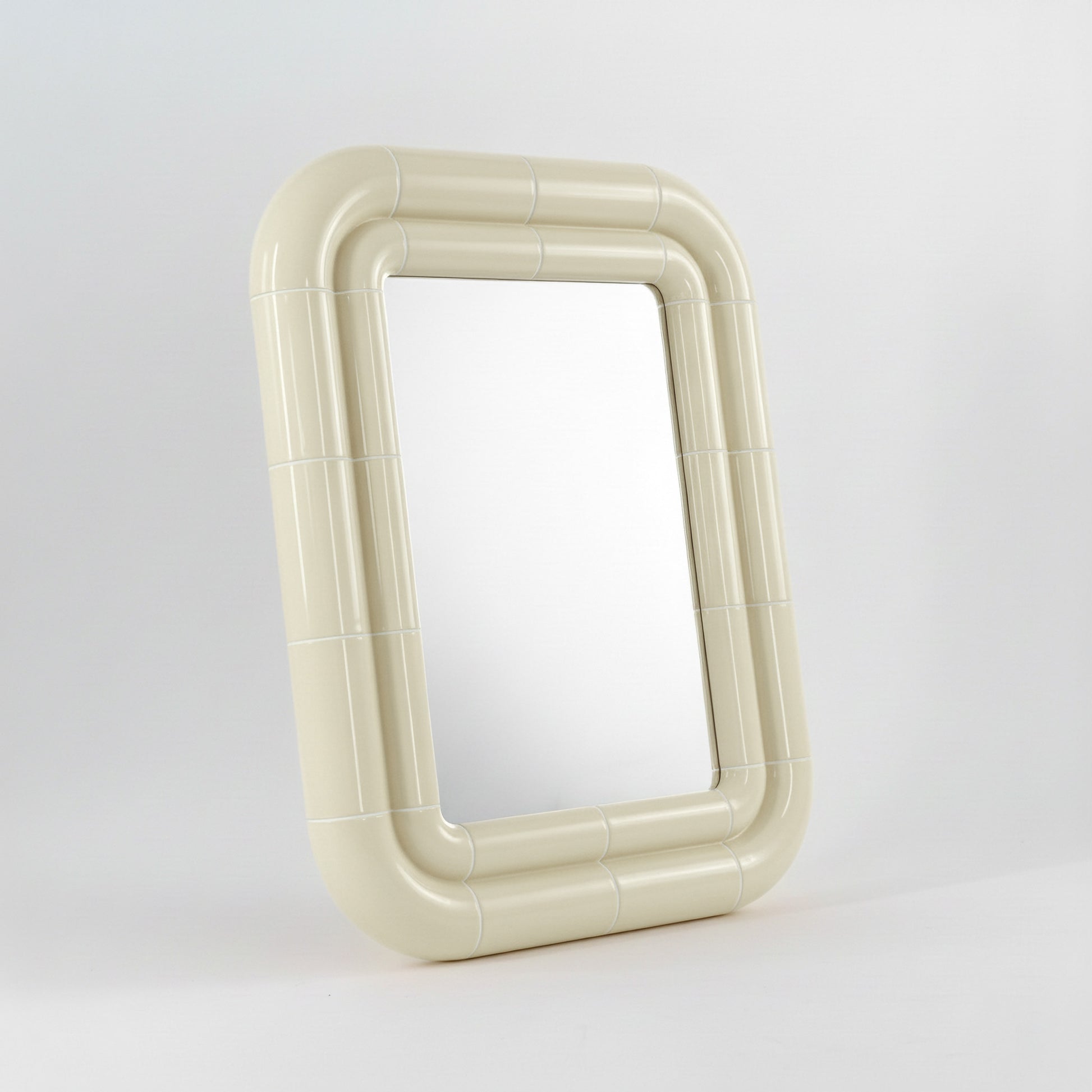 Portalito mirror in Soft Butter, sculptural tubular frame, angled view highlighting depth