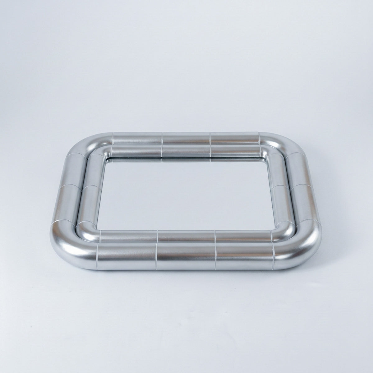 Portalito Steel mirror lying flat, showing the rounded corners and continuous tubular frame from above