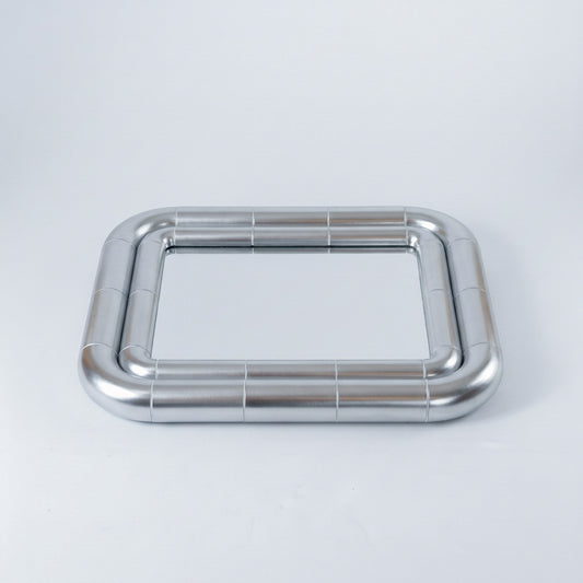 Portalito Steel mirror lying flat, showing the rounded corners and continuous tubular frame from above